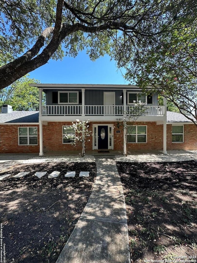 front of property featuring a balcony and brick siding