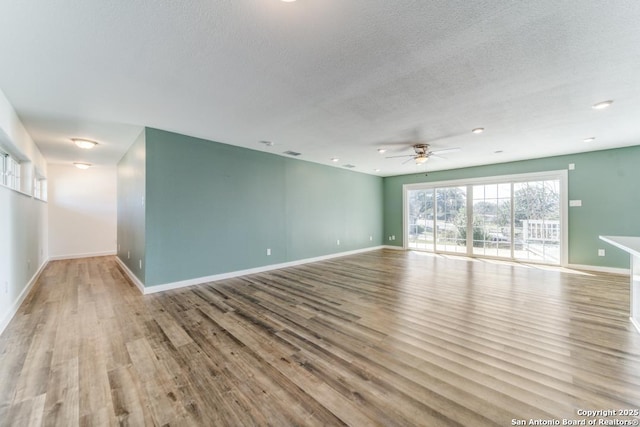 spare room featuring a textured ceiling, baseboards, and wood finished floors