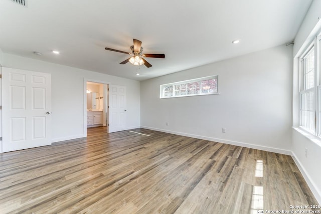 unfurnished bedroom with recessed lighting, ensuite bathroom, baseboards, and wood finished floors