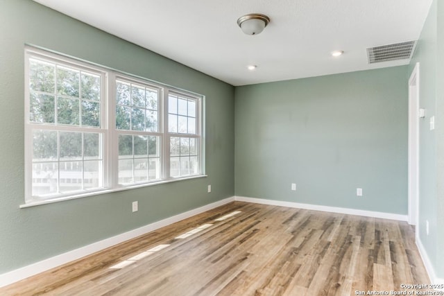 empty room with baseboards, visible vents, wood finished floors, and recessed lighting