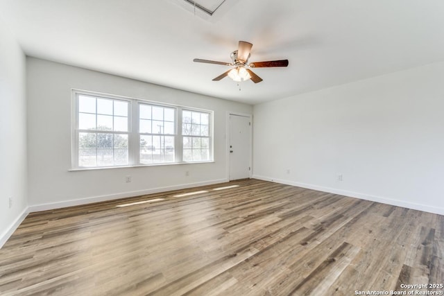 spare room featuring a ceiling fan, baseboards, and wood finished floors