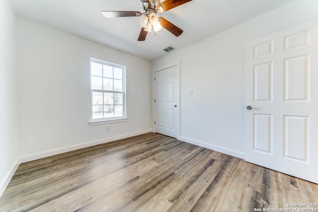 unfurnished bedroom featuring visible vents, ceiling fan, baseboards, and wood finished floors