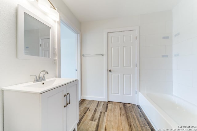 full bath with vanity, a bathing tub, and wood finished floors