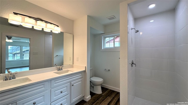 bathroom with visible vents, a tile shower, a sink, and wood finished floors