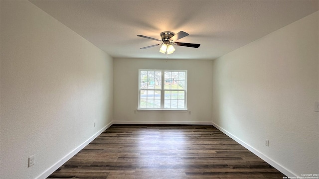 spare room featuring a textured ceiling, a textured wall, a ceiling fan, baseboards, and dark wood finished floors