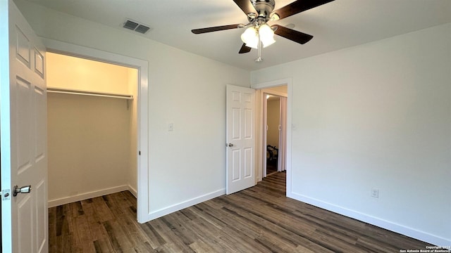 unfurnished bedroom with visible vents, baseboards, a spacious closet, a closet, and dark wood-style floors