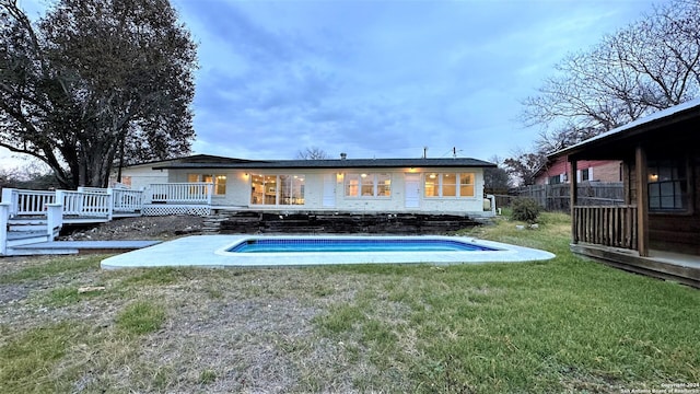 back of property with a yard, an outdoor pool, fence, and a deck