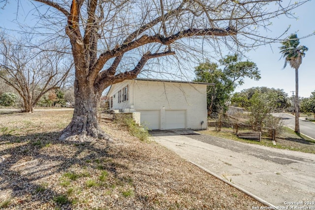 view of side of home with concrete driveway, an attached garage, and stucco siding