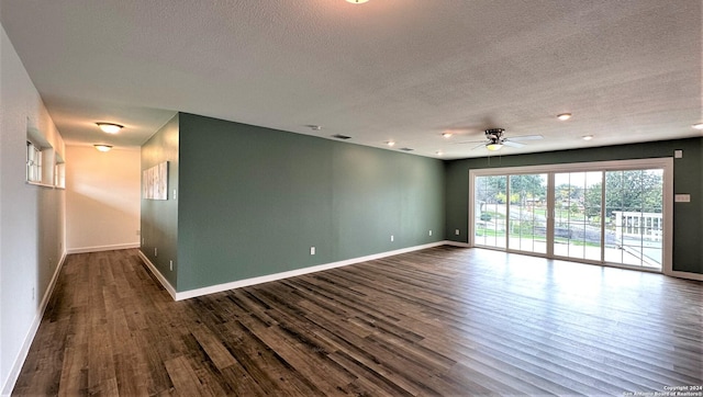 unfurnished room featuring dark wood-style floors, a textured ceiling, and baseboards