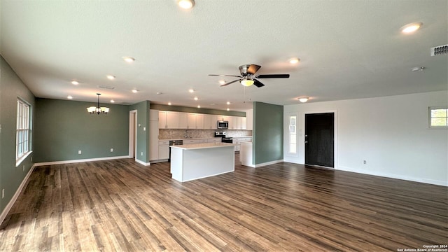 kitchen featuring open floor plan, a center island, stainless steel appliances, light countertops, and white cabinetry