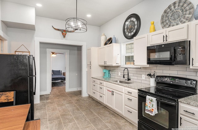 kitchen featuring tasteful backsplash, white cabinets, light stone countertops, black appliances, and a sink