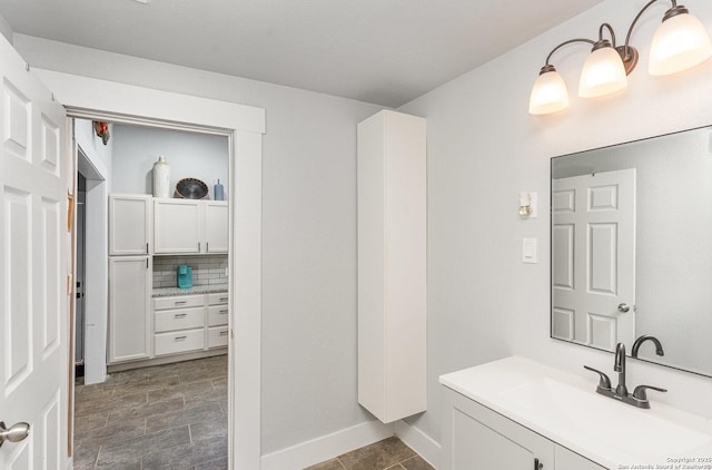 bathroom featuring baseboards, backsplash, and vanity