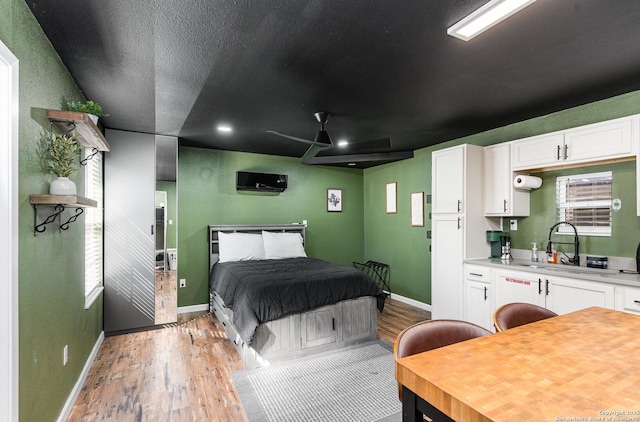 bedroom with light wood-style floors, baseboards, and a sink