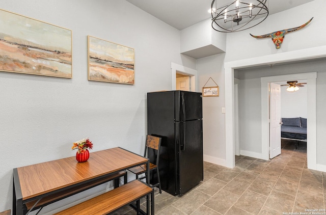 kitchen featuring ceiling fan with notable chandelier, freestanding refrigerator, and baseboards