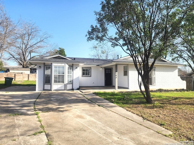 ranch-style home with concrete driveway, brick siding, and fence