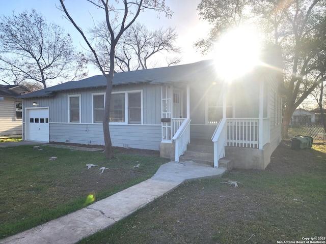 view of front of house featuring a porch, a front yard, crawl space, and a garage