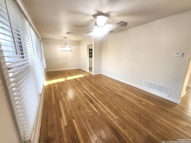 spare room featuring ceiling fan, hardwood / wood-style flooring, visible vents, and baseboards