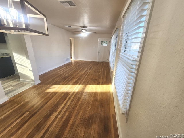 spare room featuring a textured wall, wood finished floors, visible vents, and baseboards