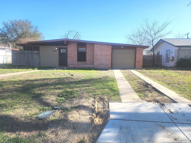 view of front of house featuring brick siding, concrete driveway, a front yard, fence, and a garage