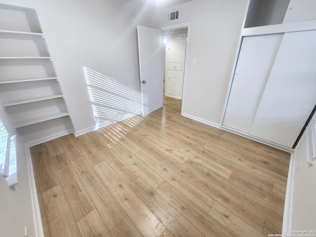 unfurnished bedroom with hardwood / wood-style floors, a closet, visible vents, and baseboards