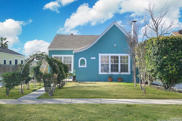 view of front of home featuring fence, a front lawn, and stucco siding