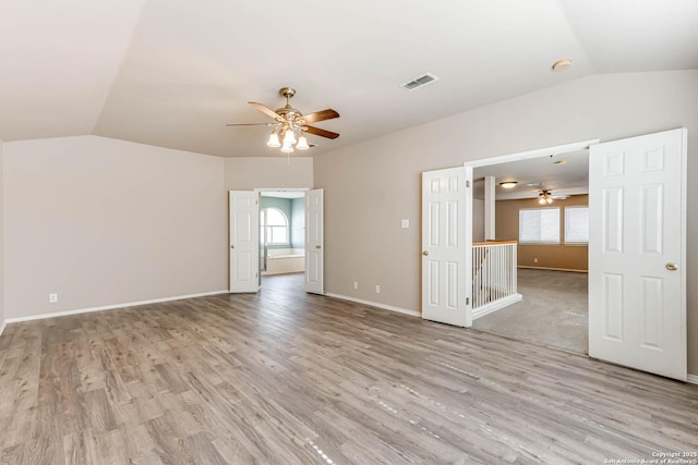 unfurnished room featuring lofted ceiling, visible vents, and light wood finished floors