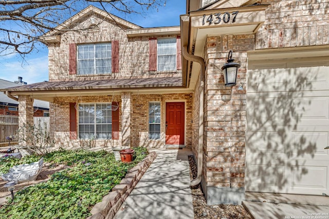 doorway to property featuring an attached garage, covered porch, and brick siding