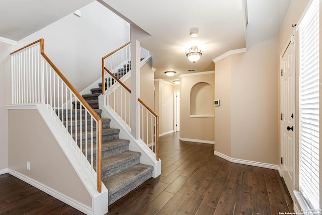 staircase with crown molding, wood-type flooring, and baseboards