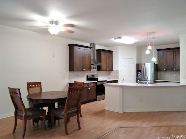 kitchen with appliances with stainless steel finishes, light countertops, dark brown cabinetry, and wall chimney range hood