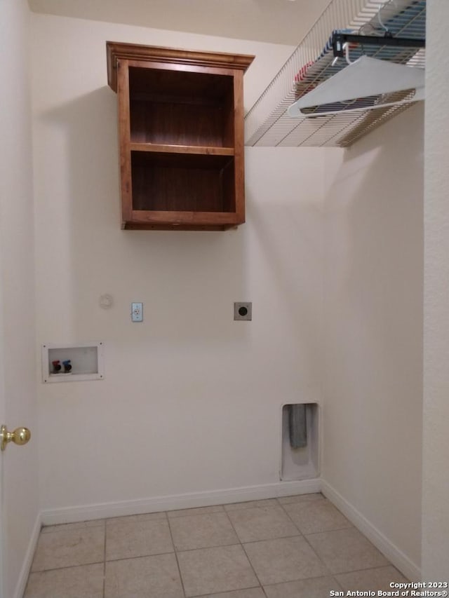 clothes washing area with laundry area, light tile patterned floors, baseboards, hookup for a washing machine, and hookup for an electric dryer