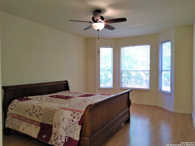 bedroom featuring ceiling fan, baseboards, and wood finished floors