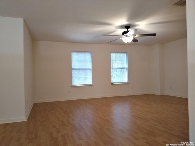 spare room with baseboards, ceiling fan, visible vents, and light wood finished floors