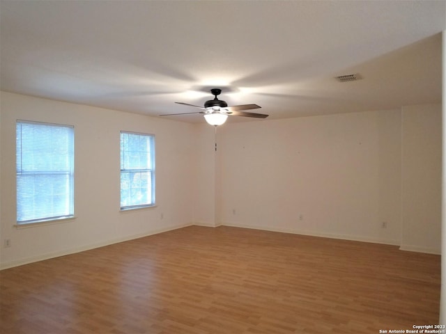 spare room with light wood finished floors, baseboards, visible vents, and a ceiling fan