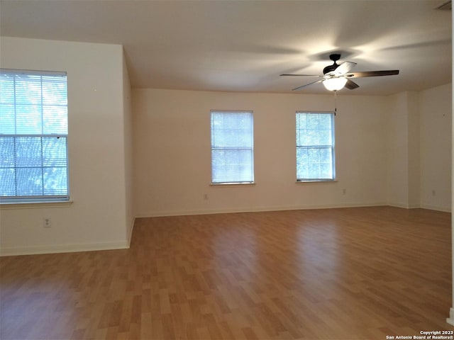 unfurnished room featuring a ceiling fan, light wood-type flooring, and baseboards