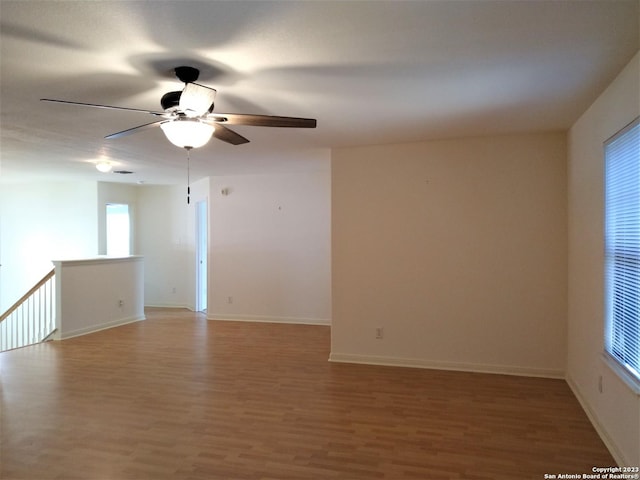 spare room with a ceiling fan, light wood-type flooring, and baseboards