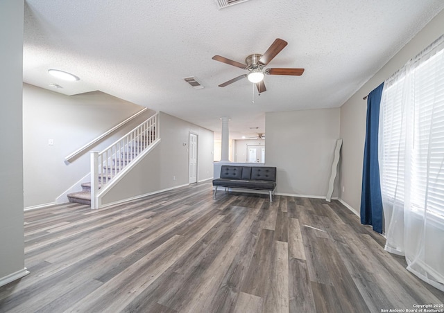 unfurnished living room featuring visible vents, ceiling fan, stairway, wood finished floors, and a textured ceiling