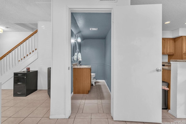 bathroom with toilet, vanity, a textured ceiling, and tile patterned floors