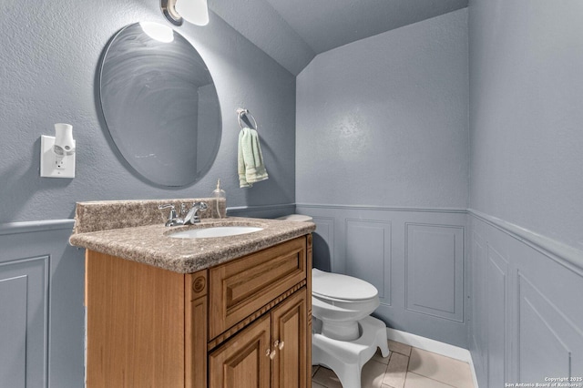 bathroom featuring tile patterned flooring, wainscoting, vanity, and toilet