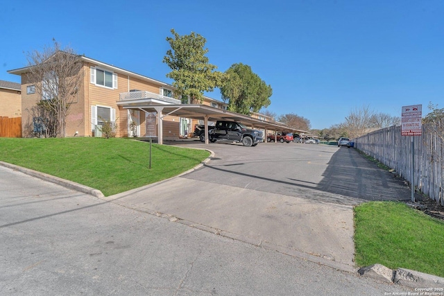 view of front of property with a front lawn, fence, and covered parking