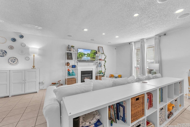 living room with light tile patterned floors, a lit fireplace, a textured ceiling, and recessed lighting