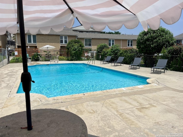 pool with a patio area and fence