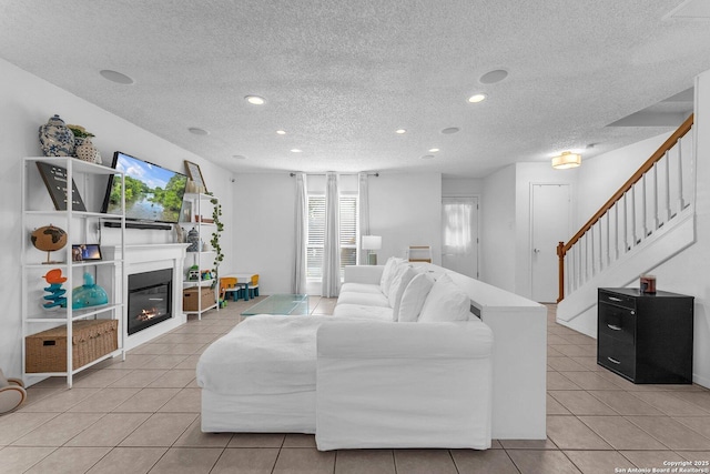 living room featuring recessed lighting, stairs, a glass covered fireplace, and light tile patterned flooring