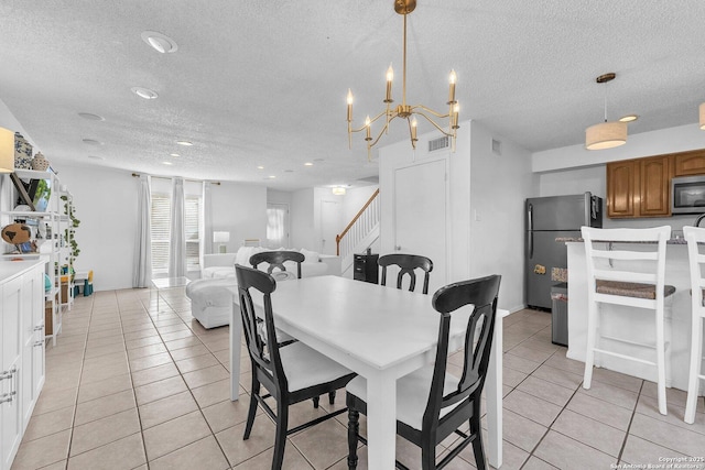 dining area featuring stairs, visible vents, a textured ceiling, and light tile patterned floors