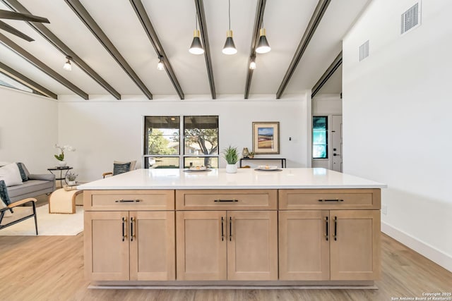 kitchen featuring visible vents, beamed ceiling, light brown cabinets, and rail lighting