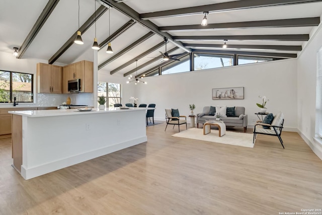 kitchen featuring stainless steel microwave, tasteful backsplash, a healthy amount of sunlight, and open floor plan