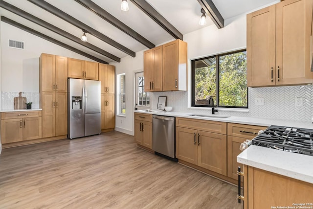 kitchen featuring a sink, appliances with stainless steel finishes, a wealth of natural light, and vaulted ceiling with beams