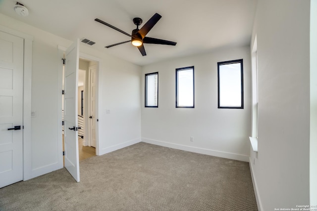 unfurnished bedroom featuring baseboards, visible vents, a ceiling fan, and light colored carpet