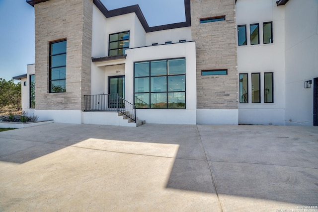 doorway to property featuring stone siding and stucco siding