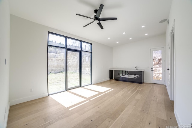 unfurnished living room with baseboards, ceiling fan, light wood-style flooring, and recessed lighting