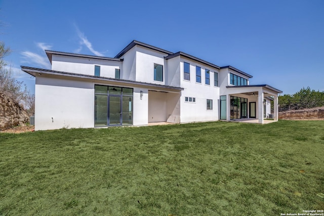 back of house featuring ceiling fan, a lawn, and stucco siding